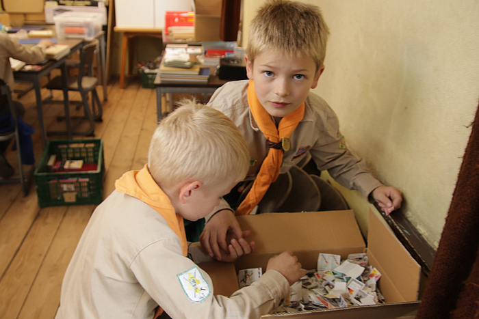 Kinder suchen wertvolle Briefmarken in einer Kiste.